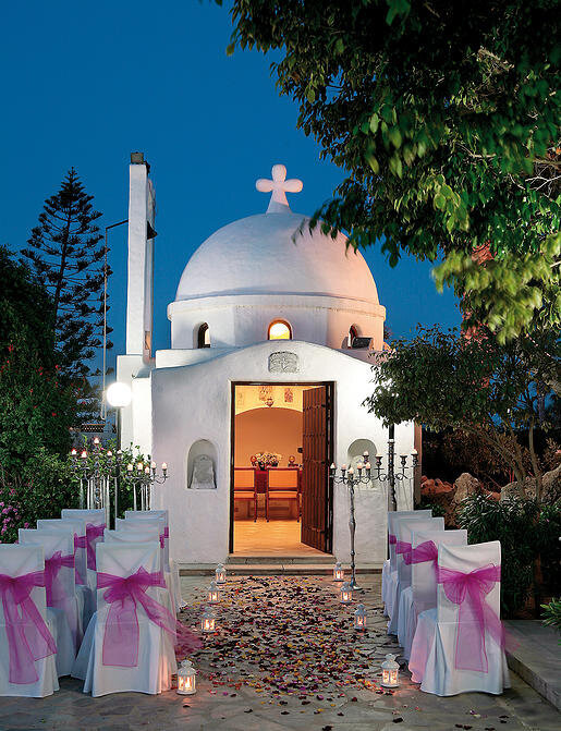 Small quaint chapel beautifully lit  against the night sky with petals covering the aisle