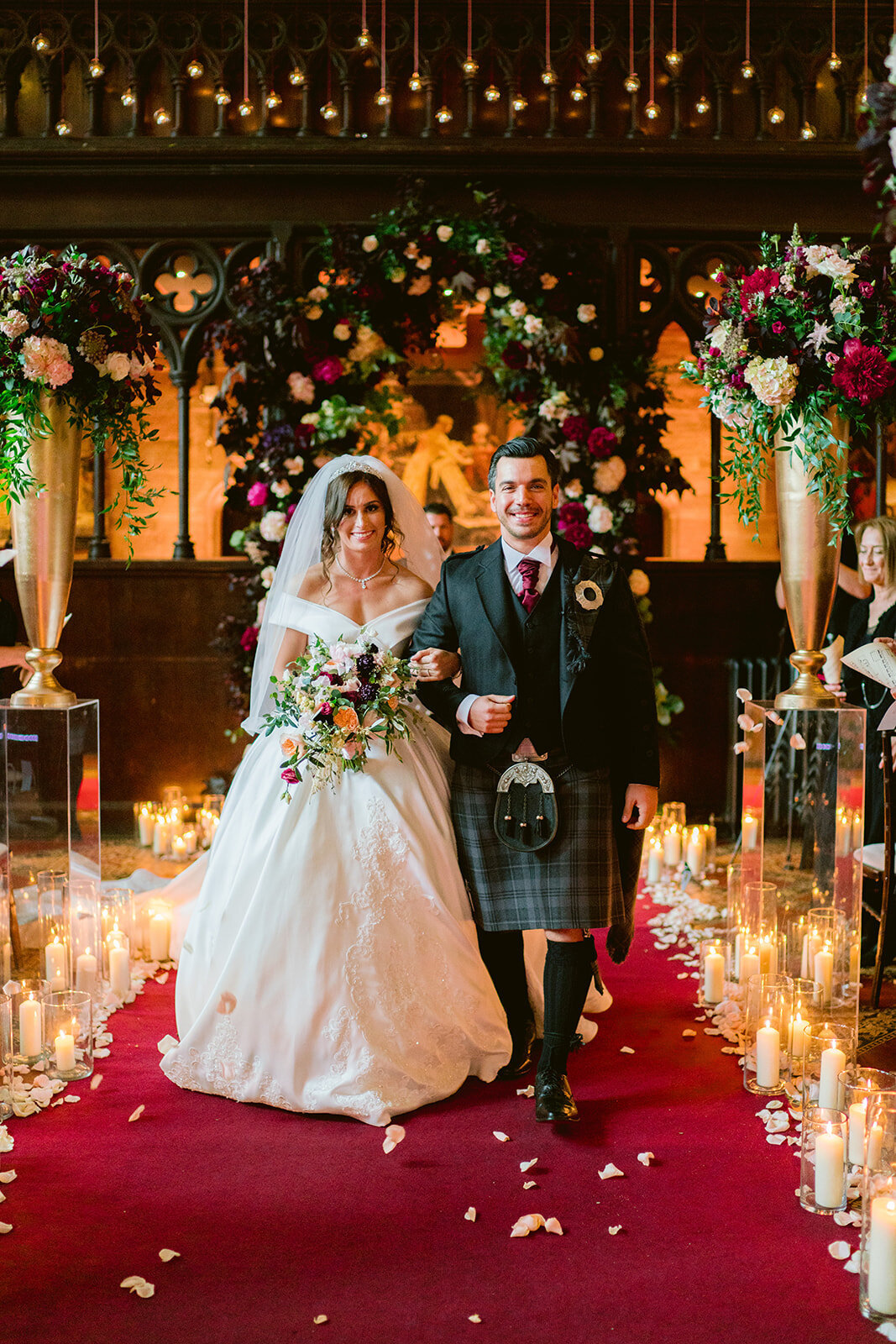 bride and groom walking on the red carpet, groom wearing a kilt at peckforton castle