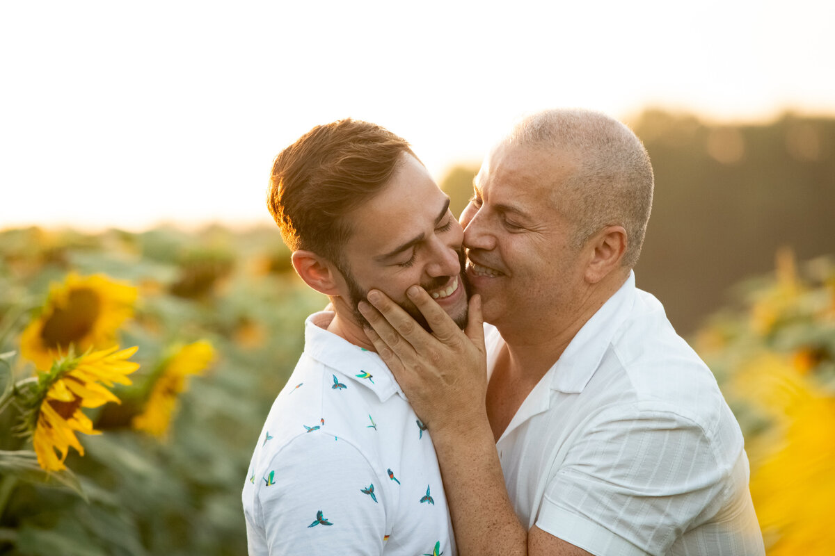 Two gay men kiss each other in a sunflower field Sunflower Valley Farm Hudson Valley engagement session New York wedding photographer