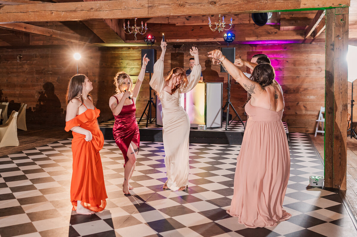 Five bridesmaids dancing on the dance floor during a wedding reception at The Peanut Warehouse enjoying their Raleigh wedding photos