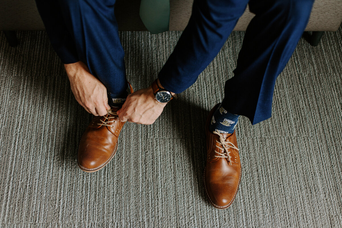 hands tying a pair of brown dress shoes