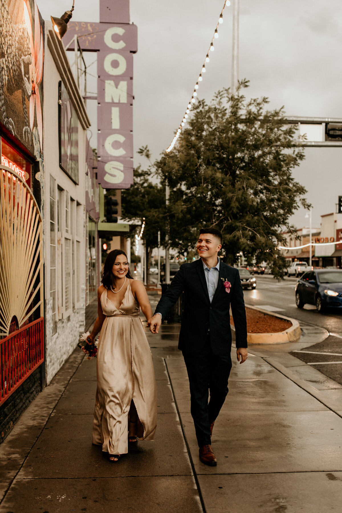 newlyweds walking down Central Ave in the rain in downtown Albuquerque