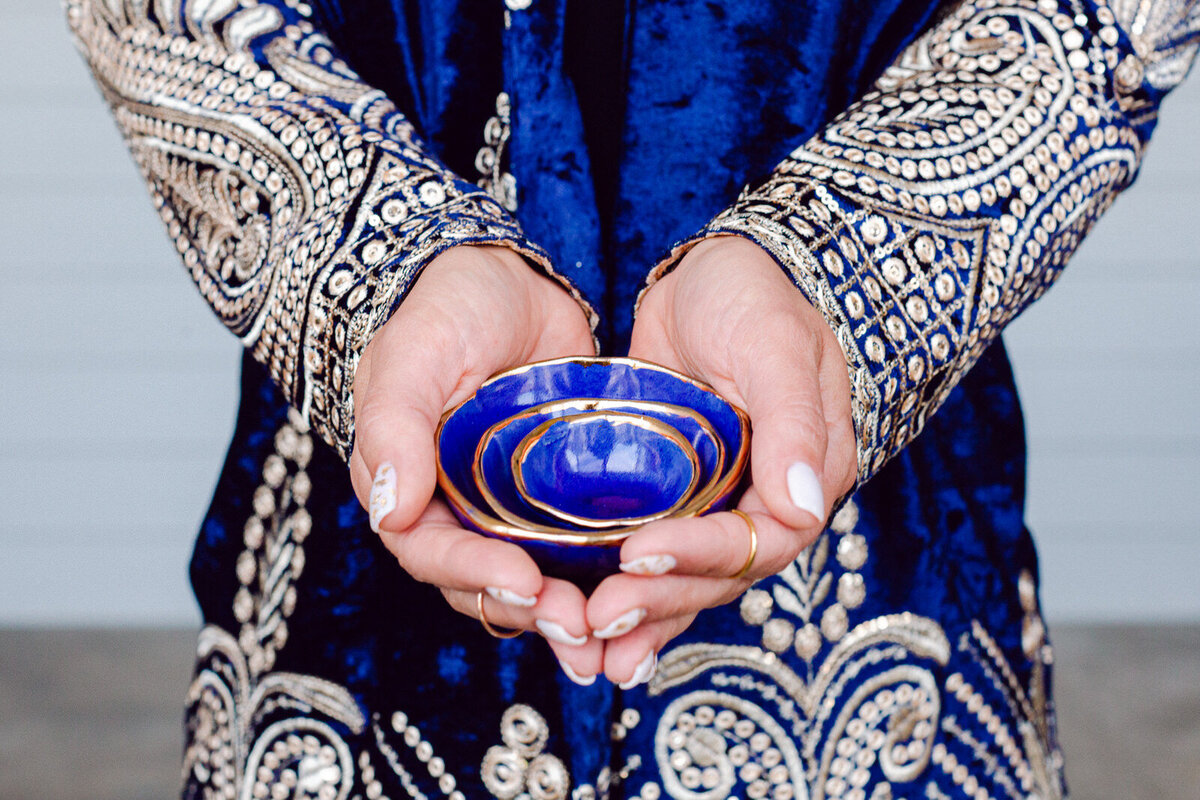 girl holding nesting bowls in blue arabian coat