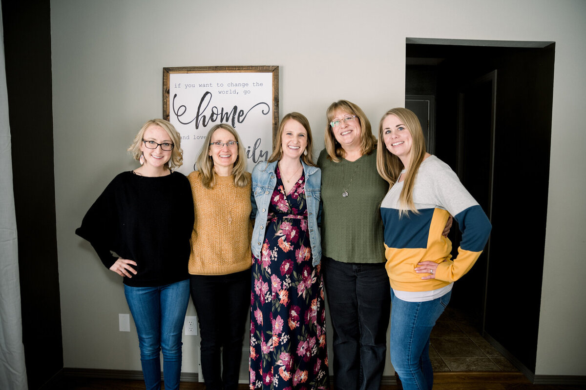 Mom-to-be posing with her guests at a pink and yellow girl baby shower, celebrating with joy and laughter.