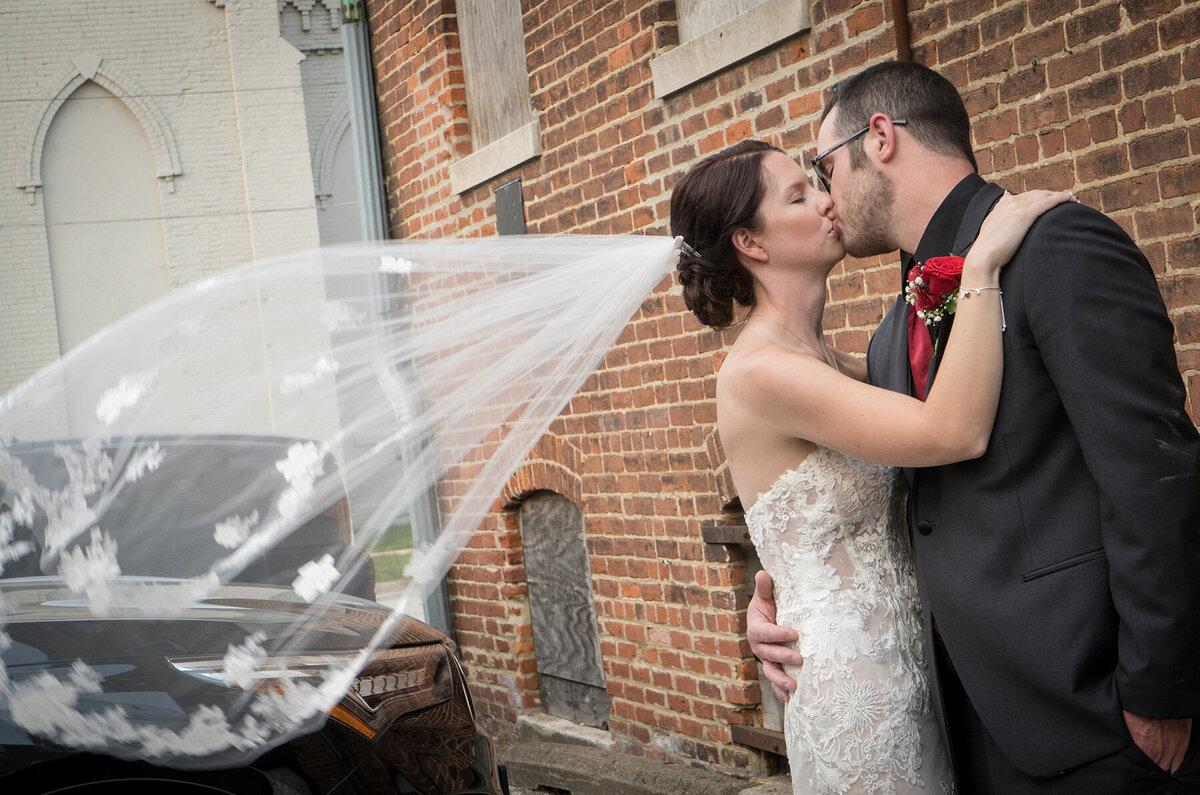 Bride kisses her groom with windswept veil
