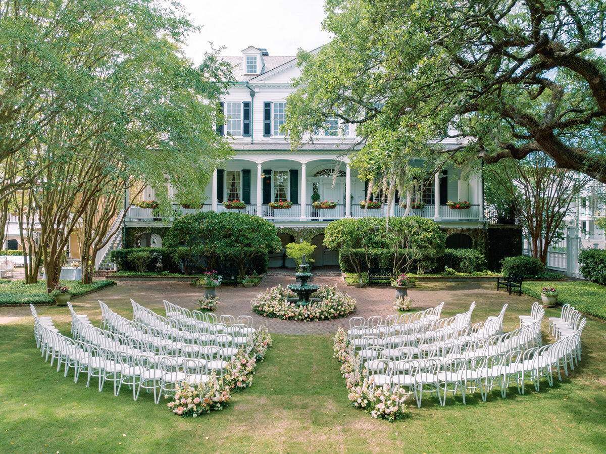 wedding ceremony at thomas bennett House facing the house. White chairs. Pink and white aisle flowers.