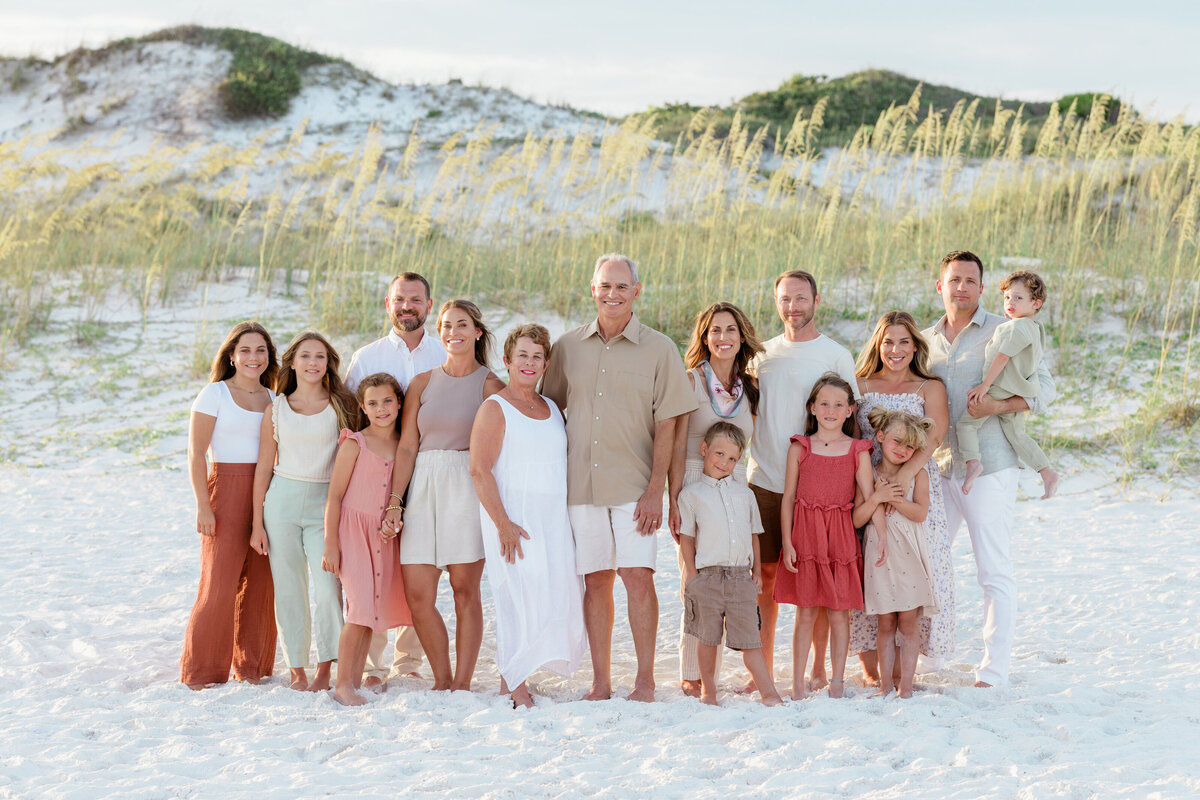 An extended family smiling together with sand dunes of Watersound Beach behind them.