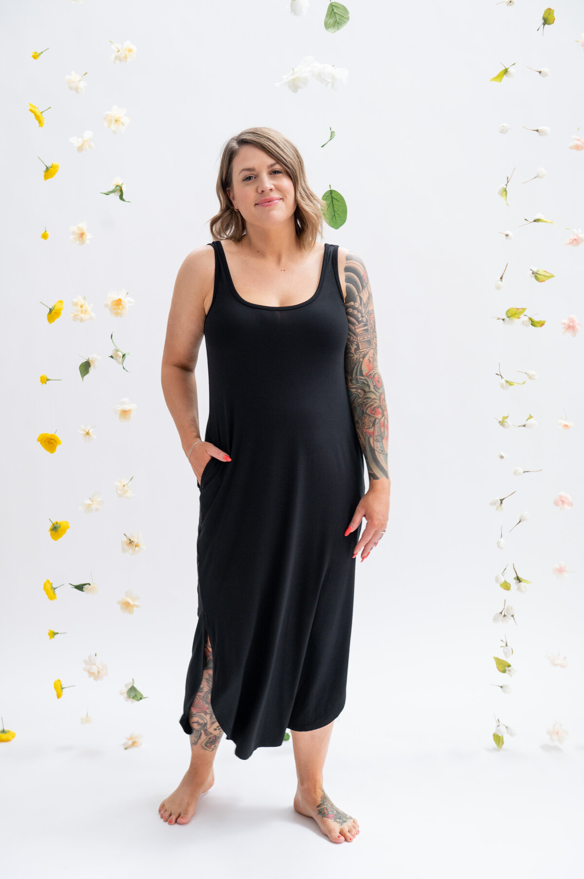 Listing photo of a woman wearing a black maxi dresses on a flower backdrop