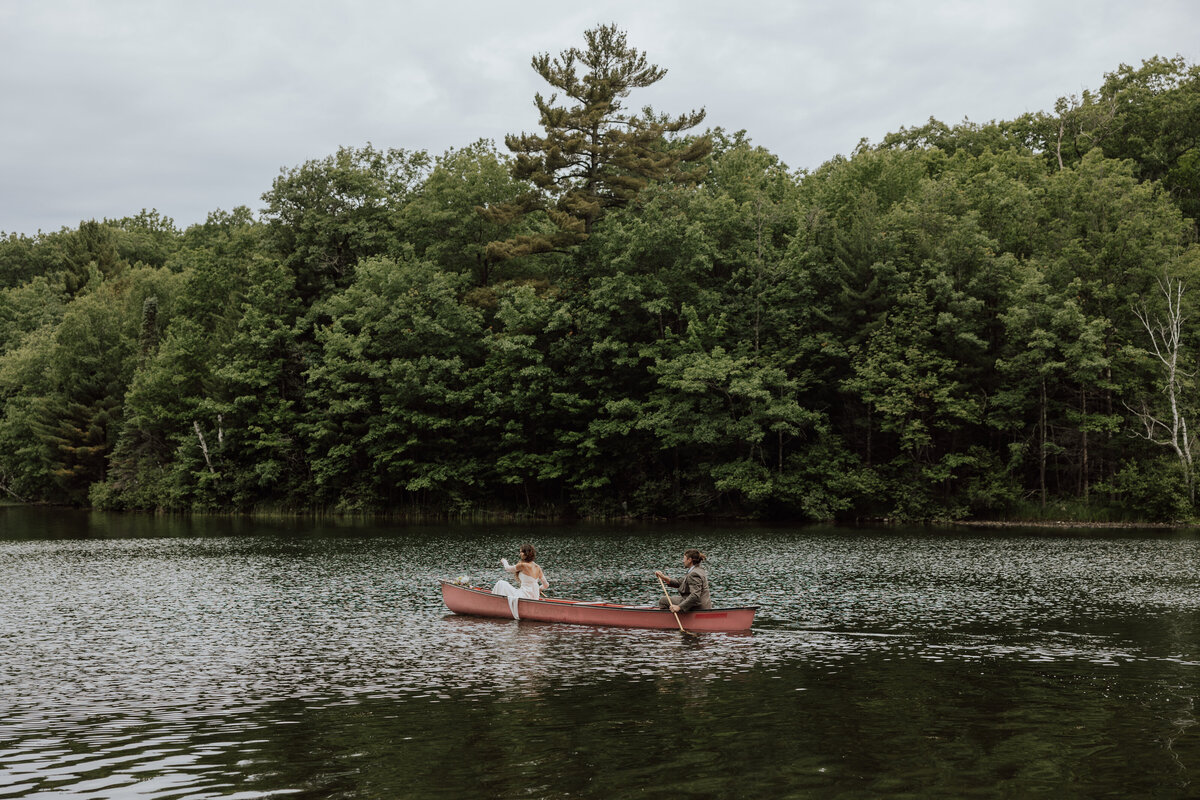 Bride and groom canoeing on a lake in Minocqua WI. Photo taken by a Wisconsin elopement photographer