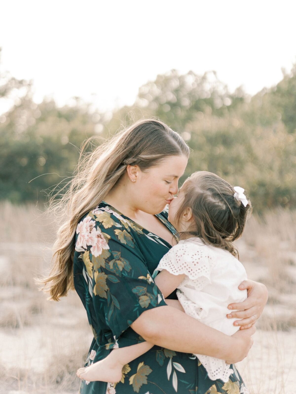 Mother kisses daughter while holder in her arms.