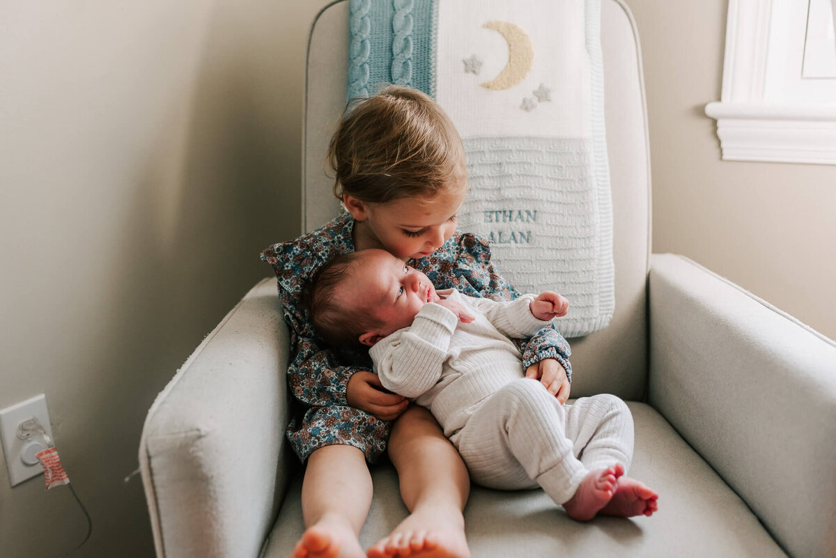 big sister holds her baby brother by Denise Van, a Northern VA newborn photographer