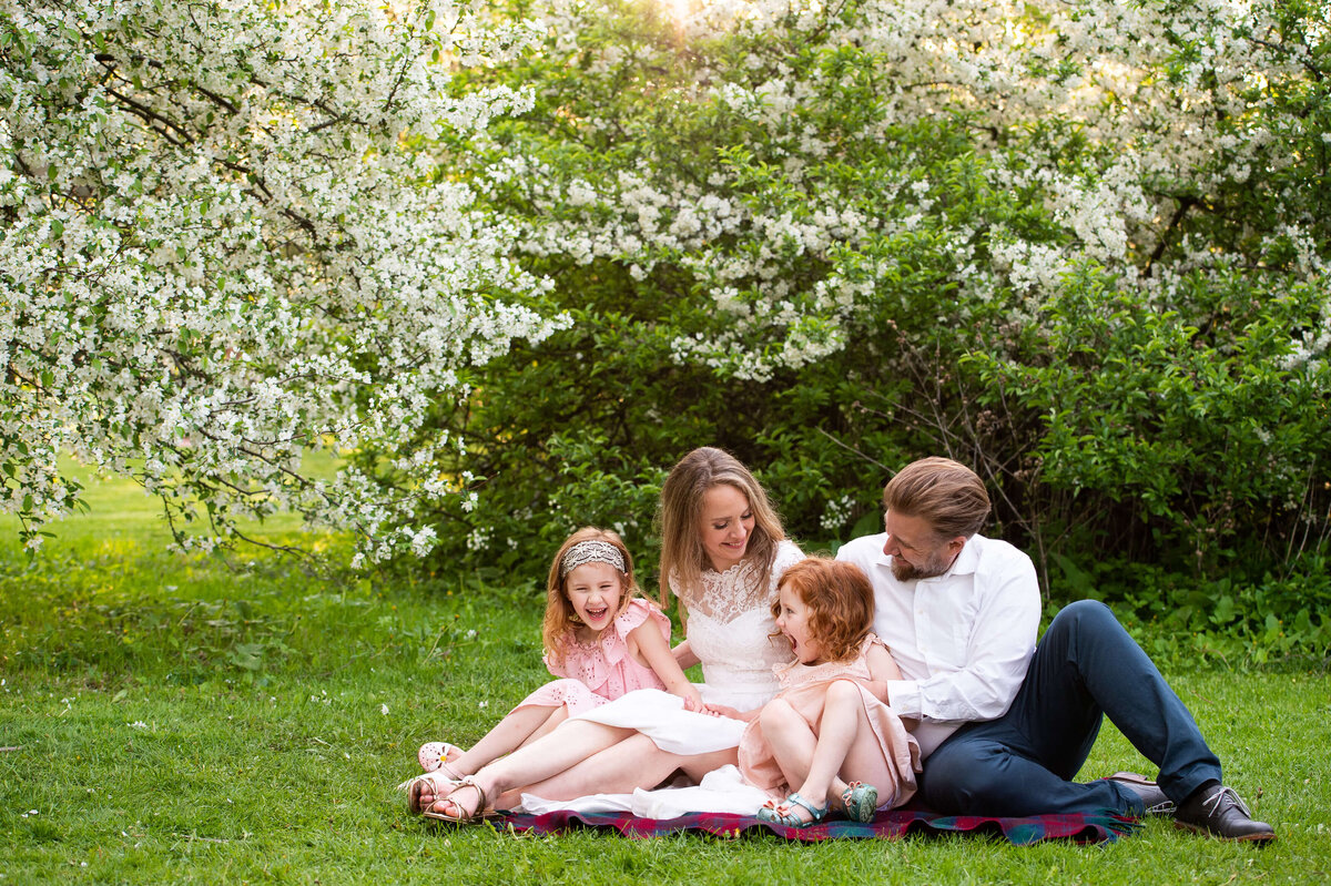 mom and dad tickling their daughters on a blanket.  Captured by Ottawa Family Photographer JEMMAN Photography