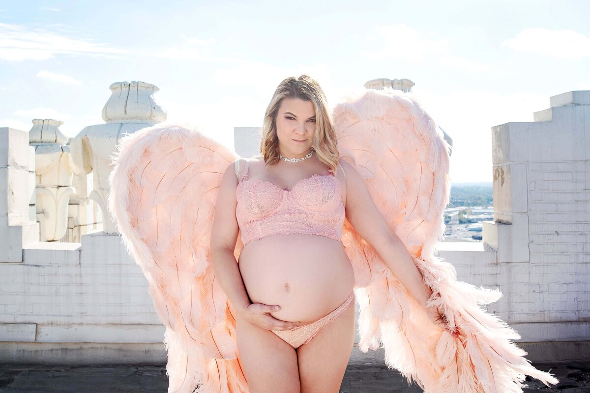 st-louis-maternity-photographer-pregnant-mom-on-st-louis-city-rooftop-wearing-pink-angel-wings