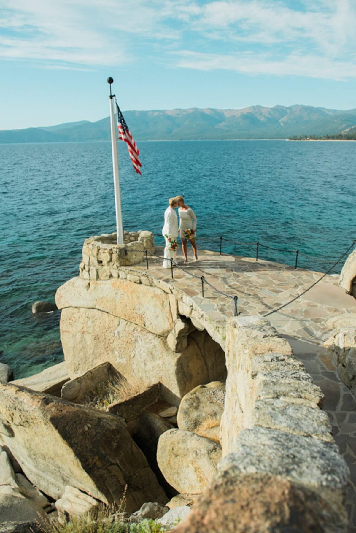 Two brides kissing at end of rock walk in Lake Tahoe at one of the historical sites Thunderbird lodge