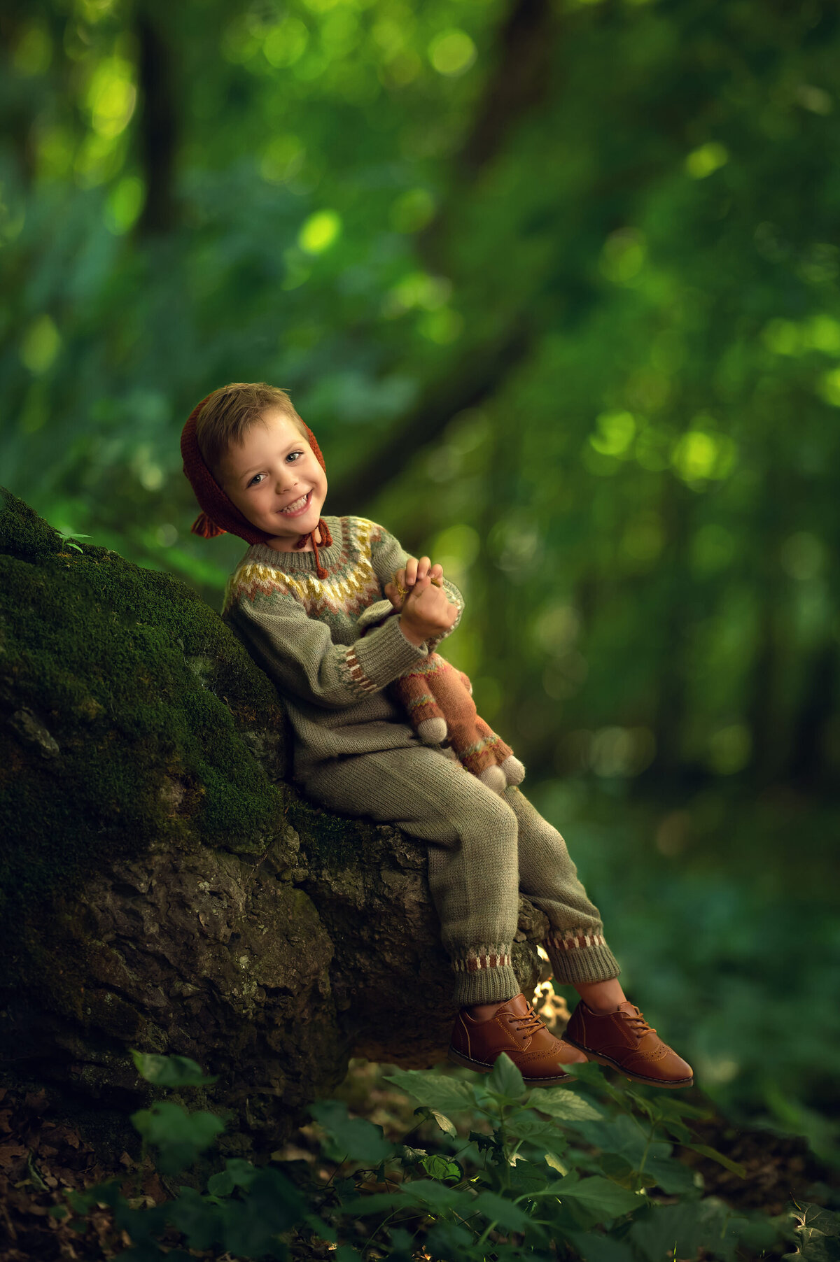 A young boy in green, organic costuming poses with his stuffed animal in our fantasy-inspired enchanted forest portraits.