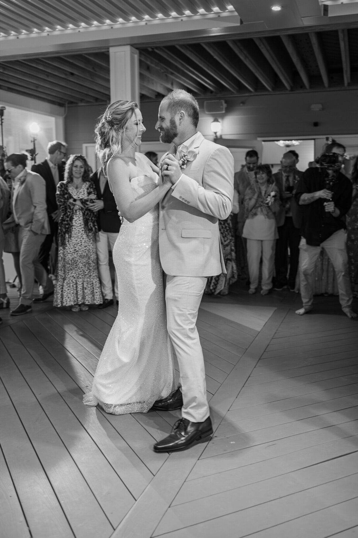 A bride and groom enjoying a first dance surrounded by family and friends at their wedding reception by Raleigh wedding photographer, JoLynn Photography