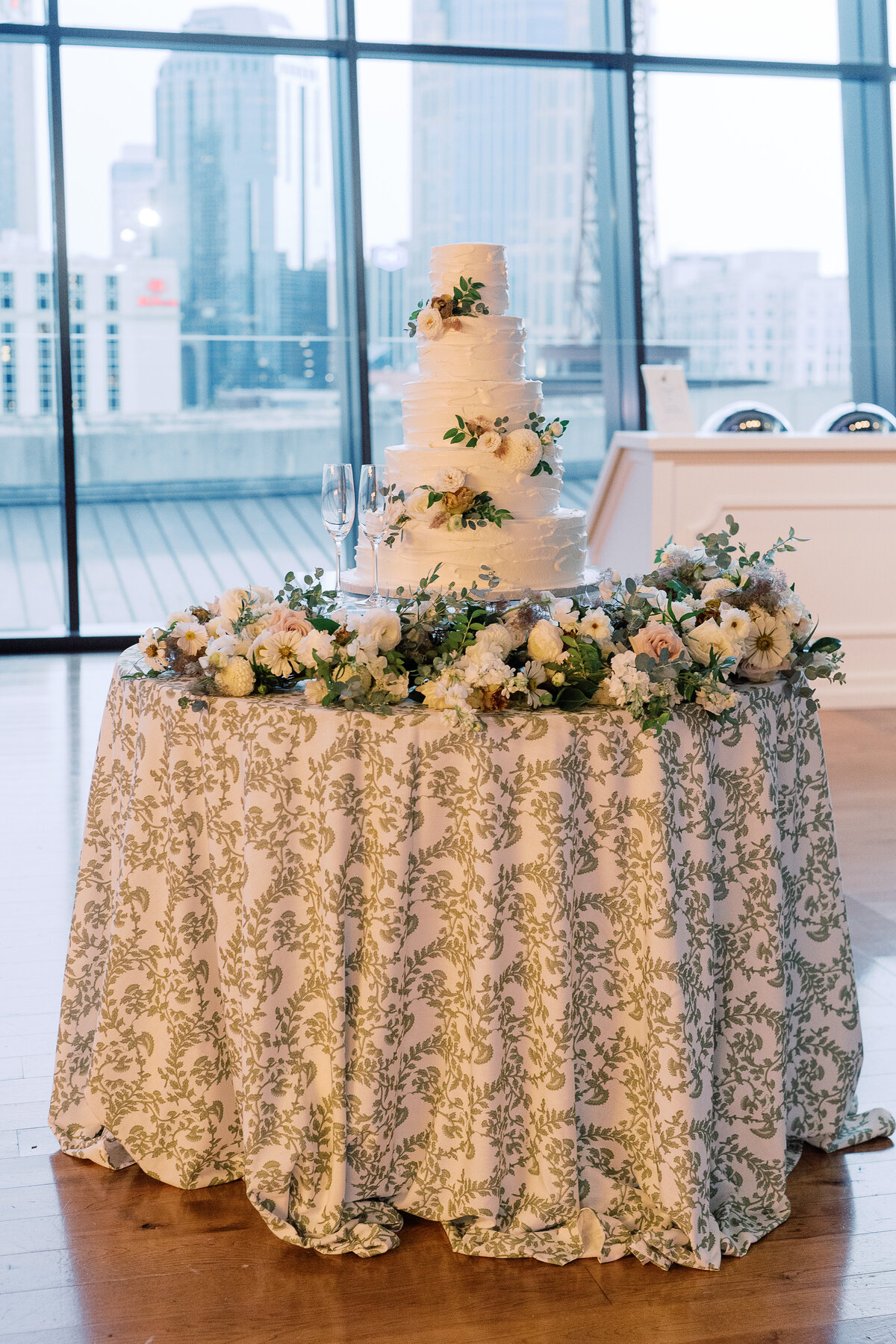 Elegant cake flowers for timeless garden-inspired summer wedding. Classic white, cream, and green floral colors accent multi-tiered cake in downtown Nashville. Design by Rosemary & Finch Floral Design.