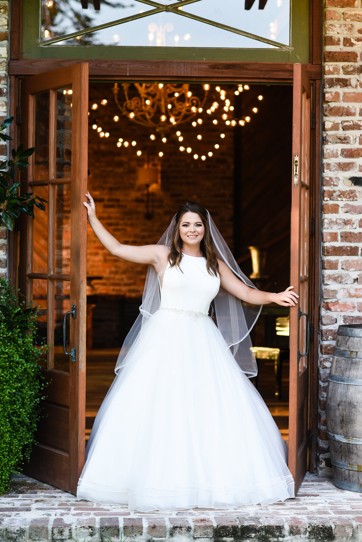 Beautiful bridal portrait photography: bride stands in between french doors at Green Gates Farmhouse venue in Mississippi