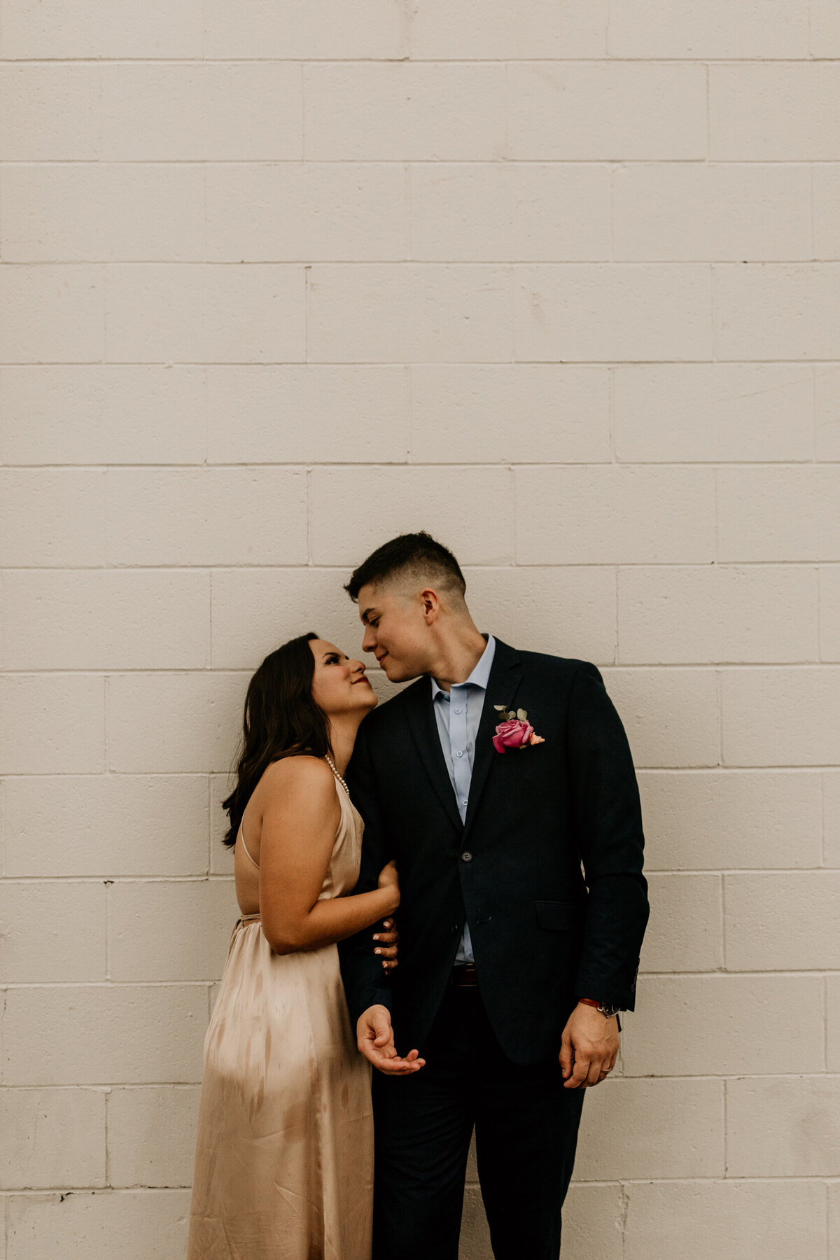 bride and groom about to kiss in front of a white brick wall in New Mexico