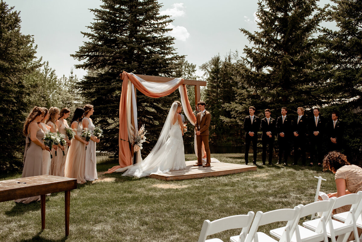 Outdoor wedding ceremony at Pine & Pond, a natural picturesque wedding venue in Ponoka, AB, featured on the Brontë Bride Vendor Guide.