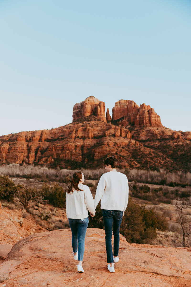 couple holds hands with sweaters on for winter engagement shoot in sedona