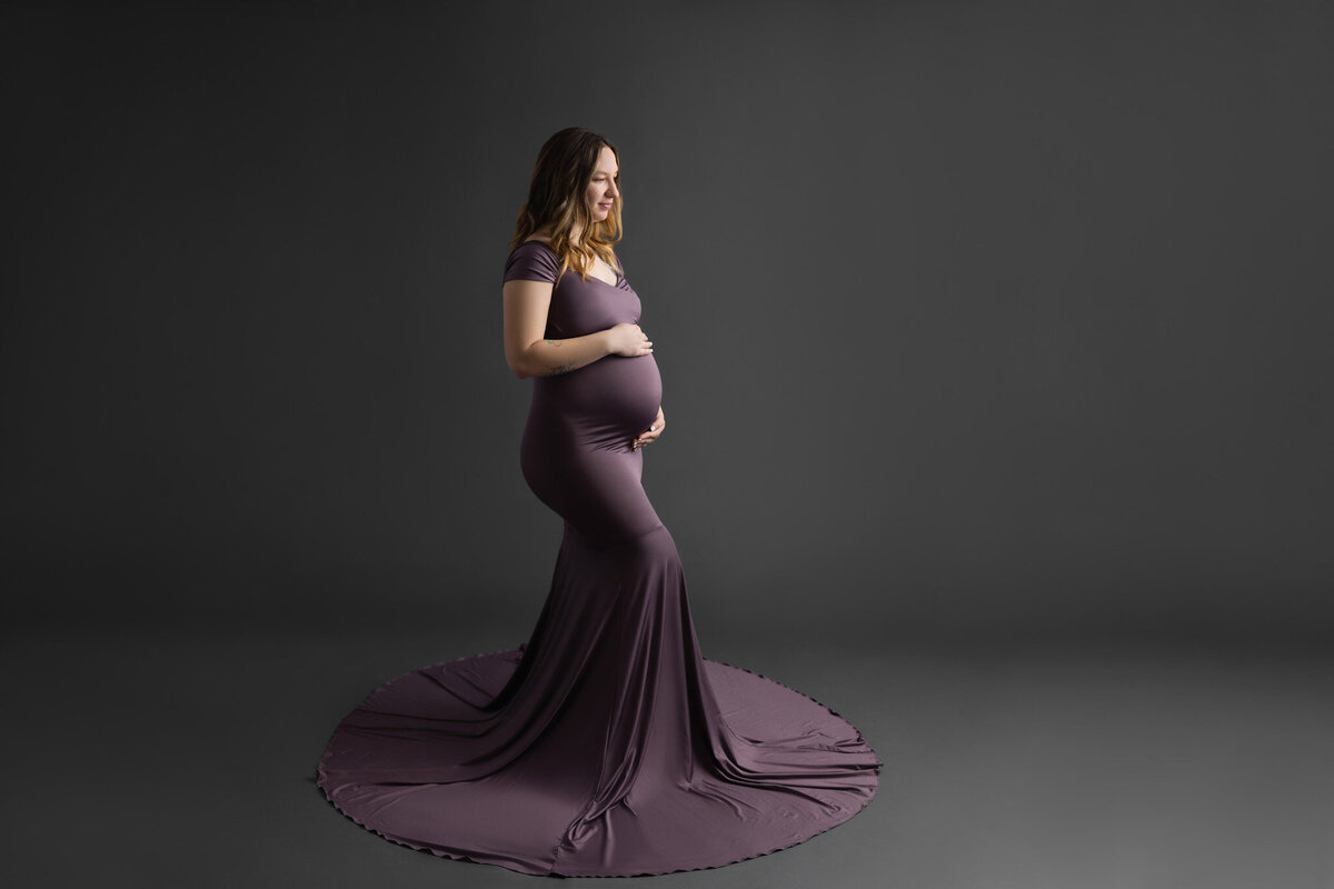 pregnant woman in a purple dress holding her belly