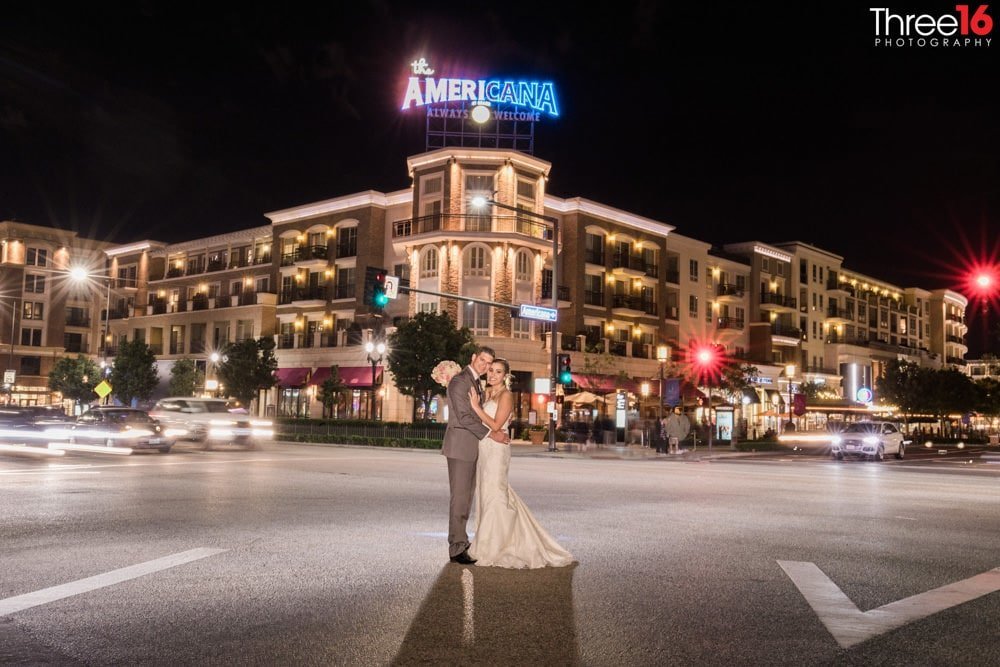 Bride and Groom pose together at night in the middle of a crosswalk during a busy intersection