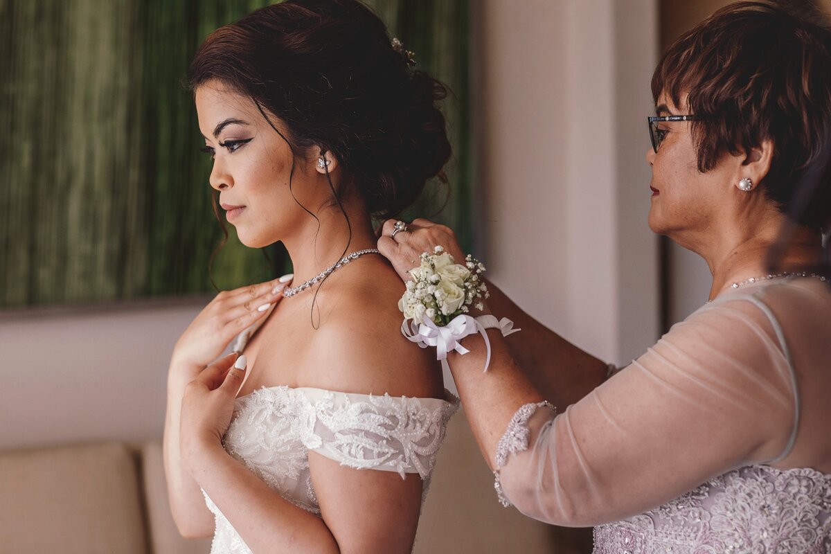 Mother helping bride with necklace at wedding in Cancun