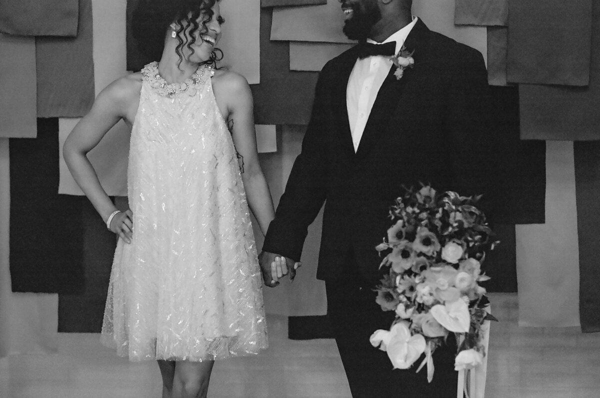 A black and white photo of a couple holding hands and smiling.