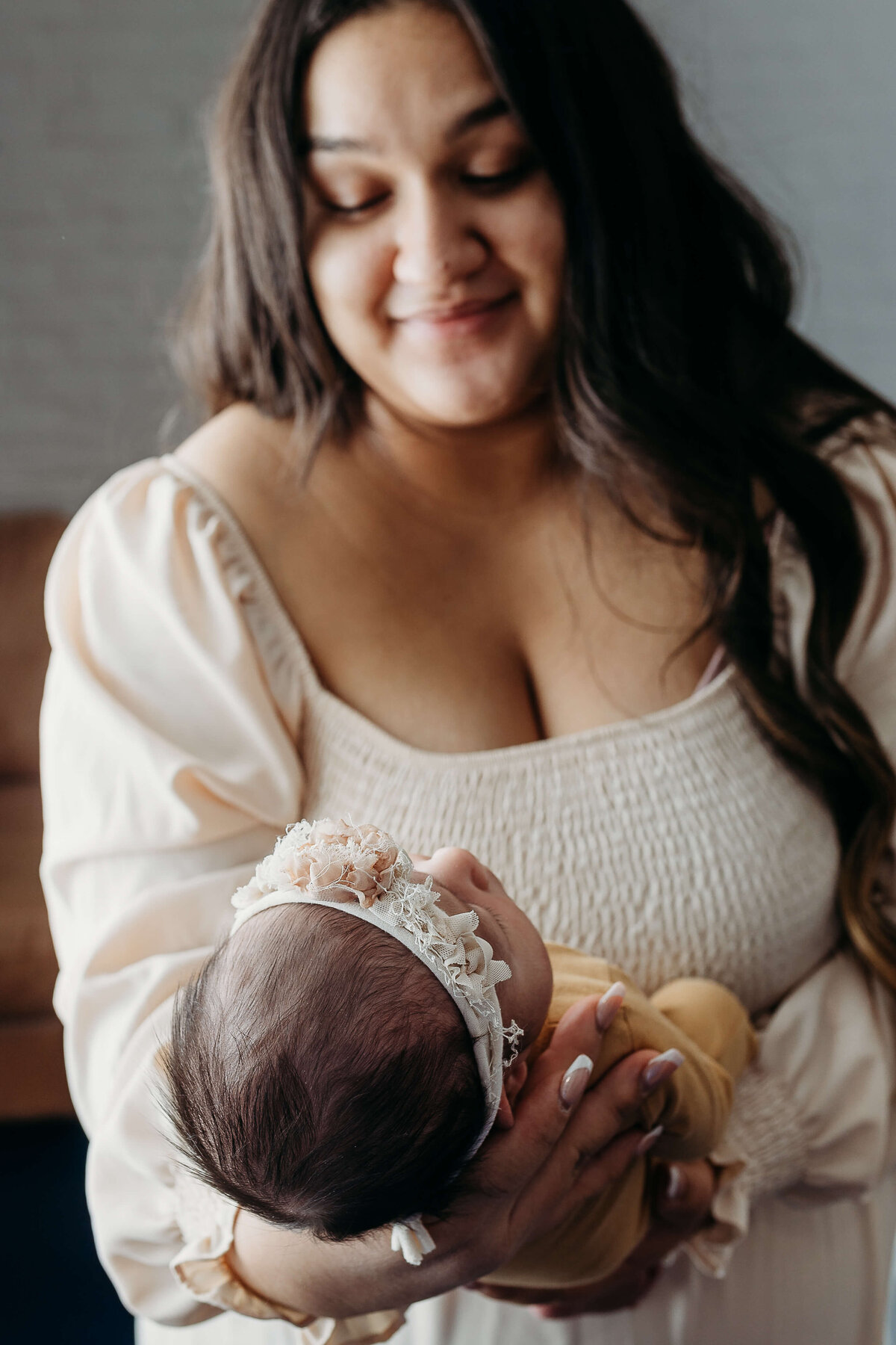 New mother holding little newborn and smiling.