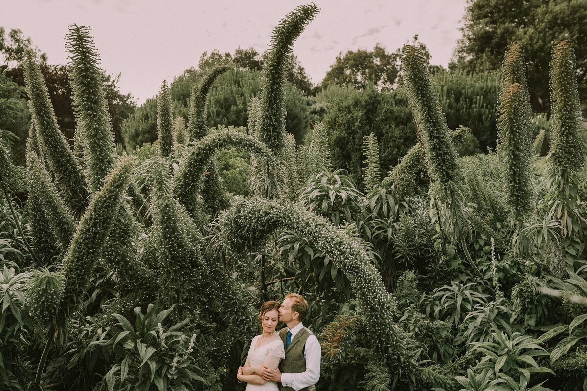 A couple kissing among plants in a botanical garden
