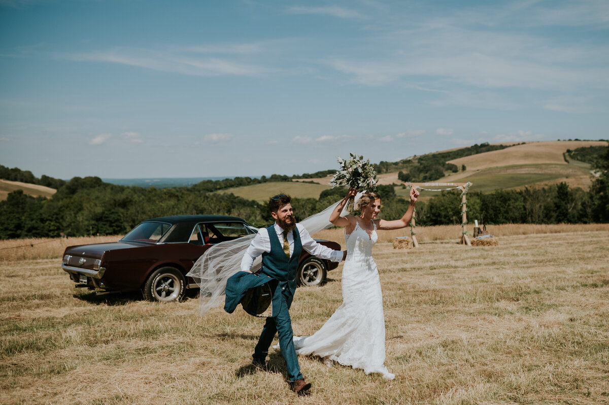 Couple celebrating in field with classic car