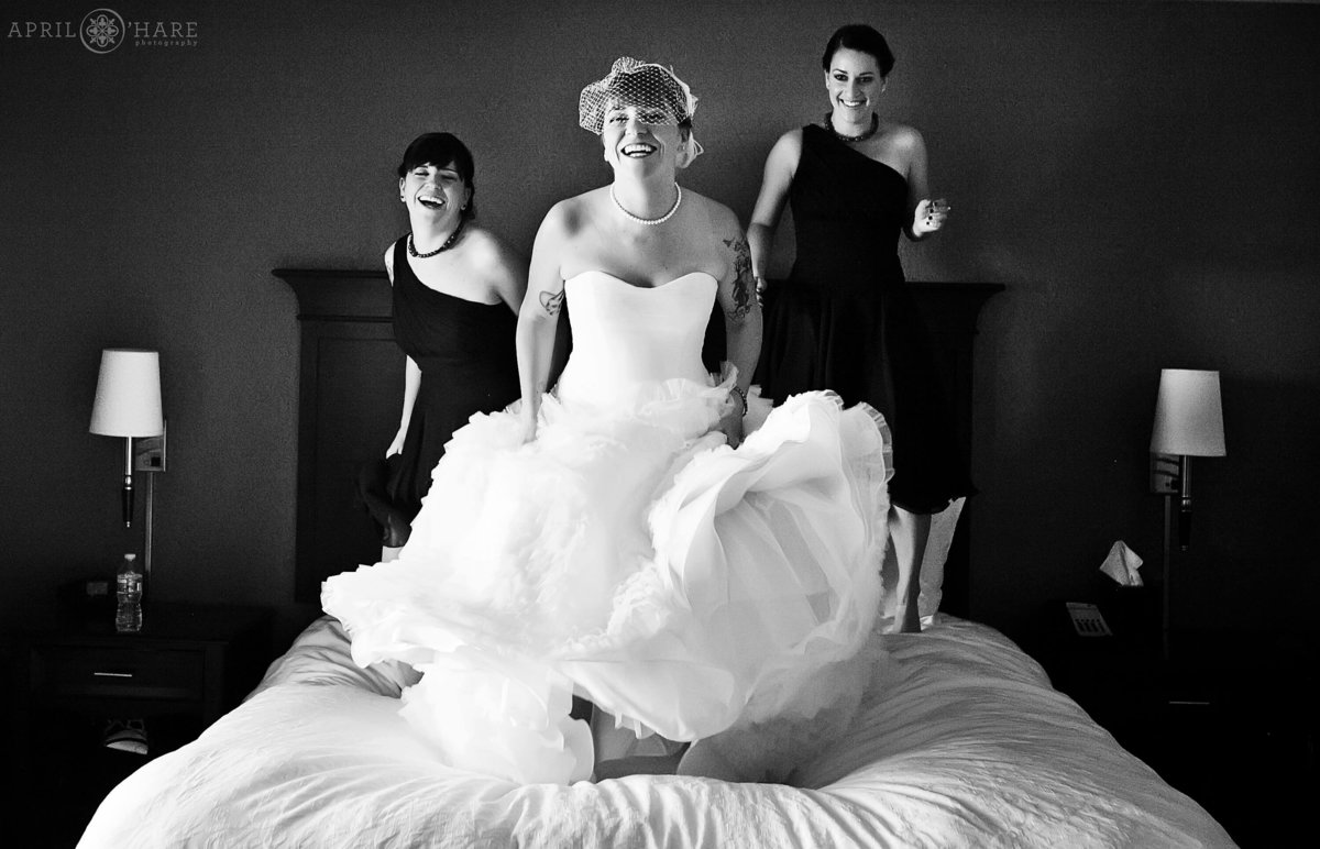 Silly Fun Photo of a Bride Jumping on her hotel bed in Denver Colorado in B&W