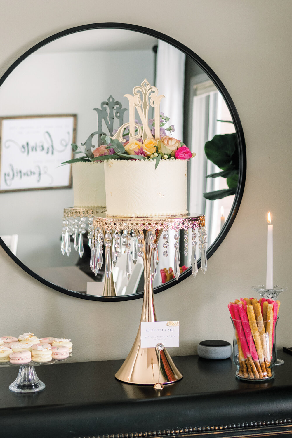 Charming dessert table for a pink and yellow girl baby shower featuring a cake on a rose gold stand, yellow and pink macarons, and pink and yellow pretzels dipped in sugar crystals.