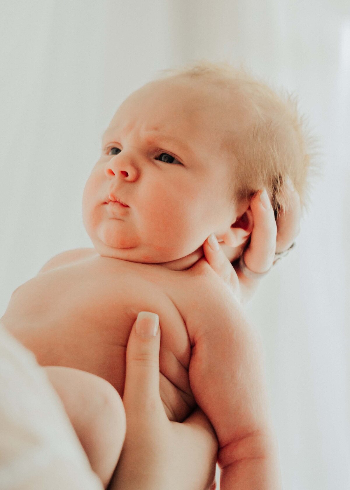 Maddie Rae Photography naked baby with a grumpy face looking at mom