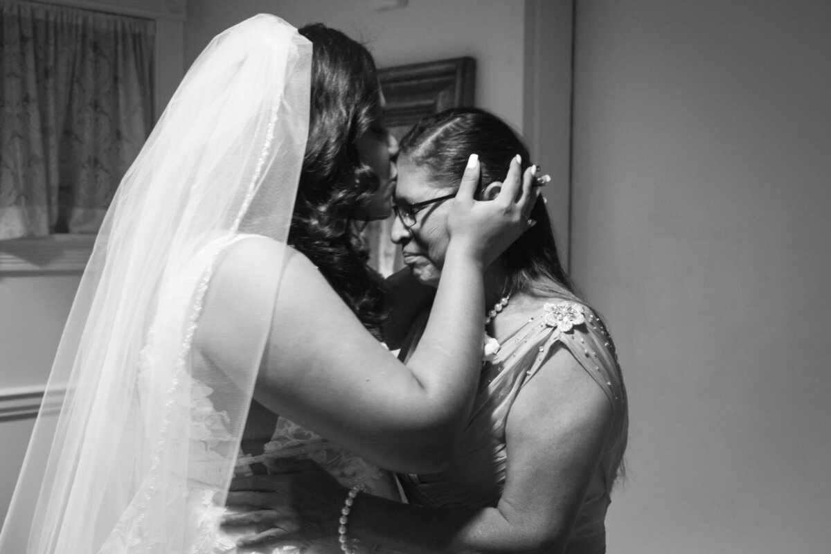 black and white image of bride kissing mothers forehead