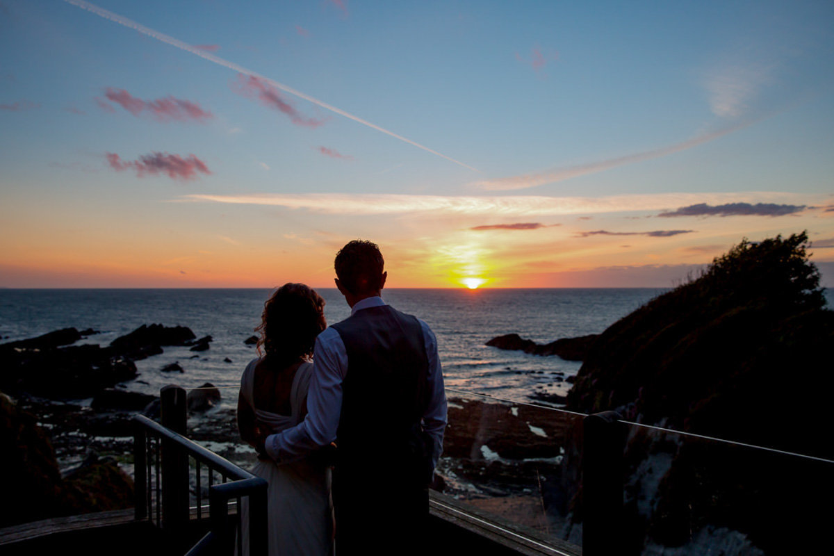 Married couple watching Sunset at Tunnels Beaches Wedding in Devon