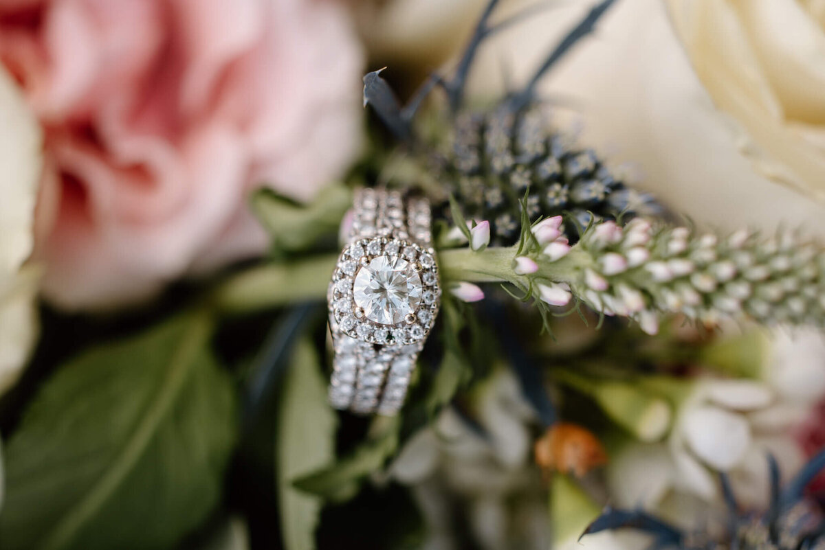 Detail photograph of bride's diamond wedding ring sitting in bridal bouquet