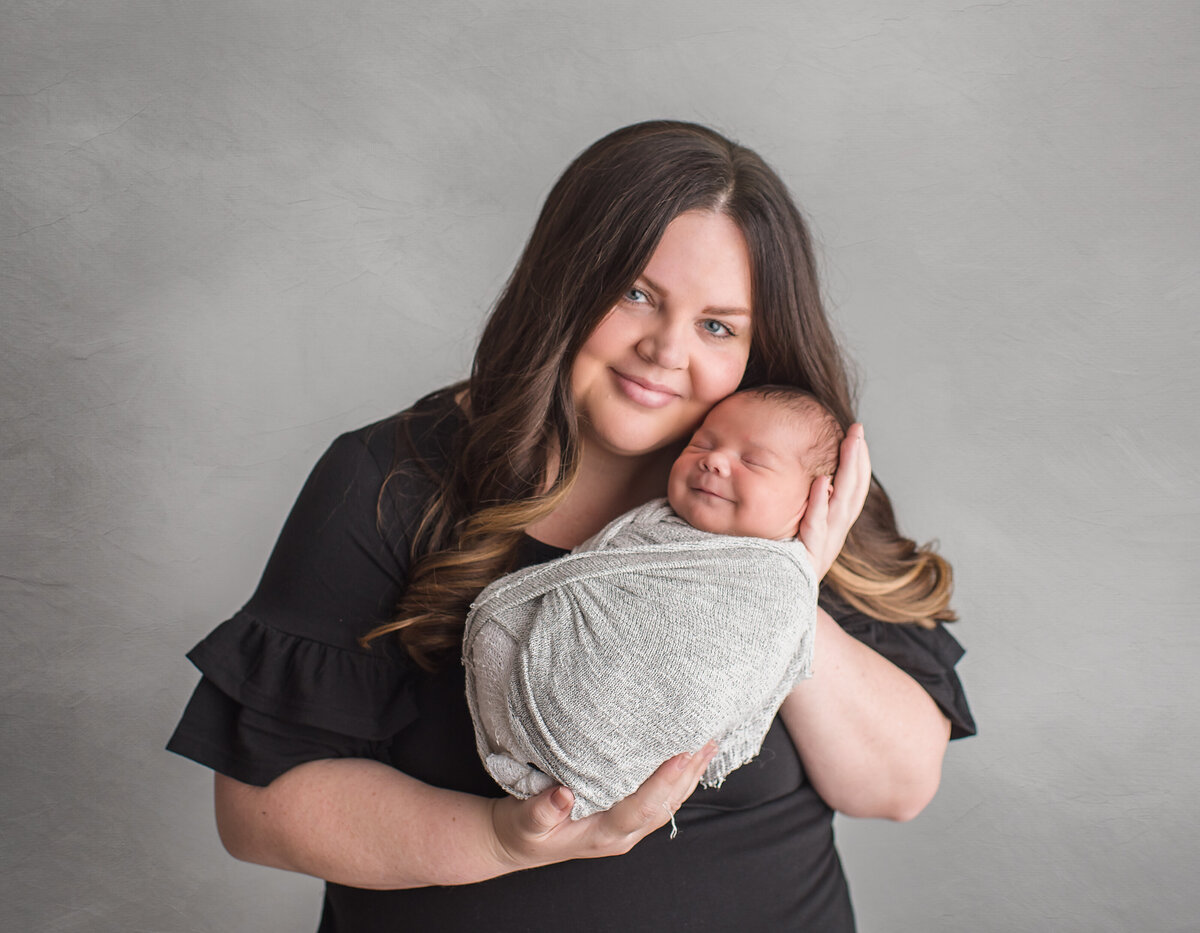 mom dressed in black with baby held in hand