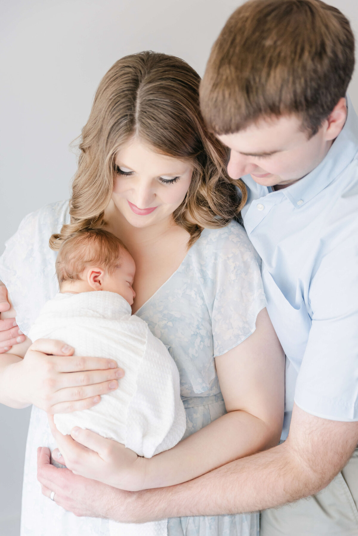 beautiful couple looking down at newborn baby boy in light and airy cedar falls photography studio