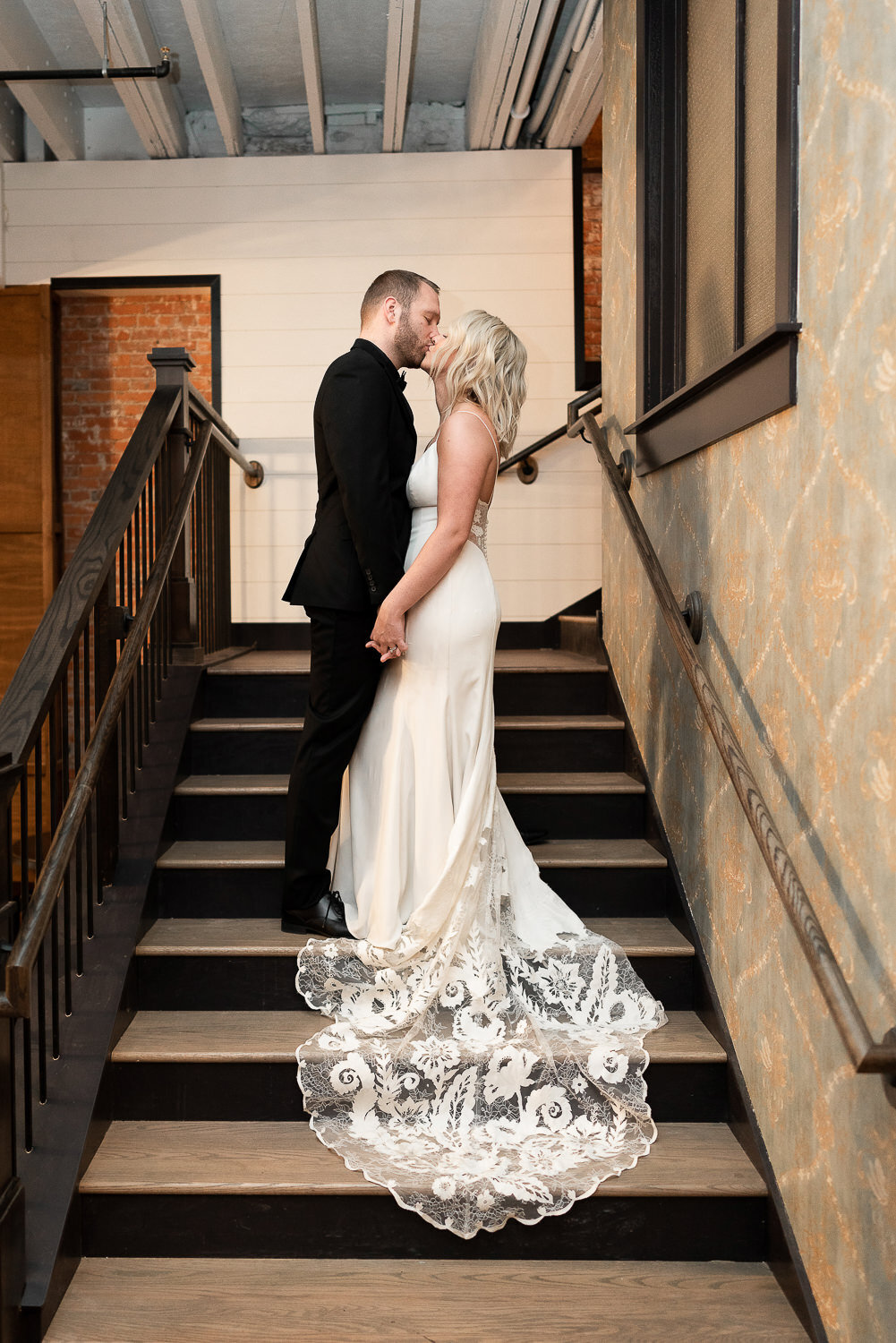 Bride and groom kiss on the stairs.
