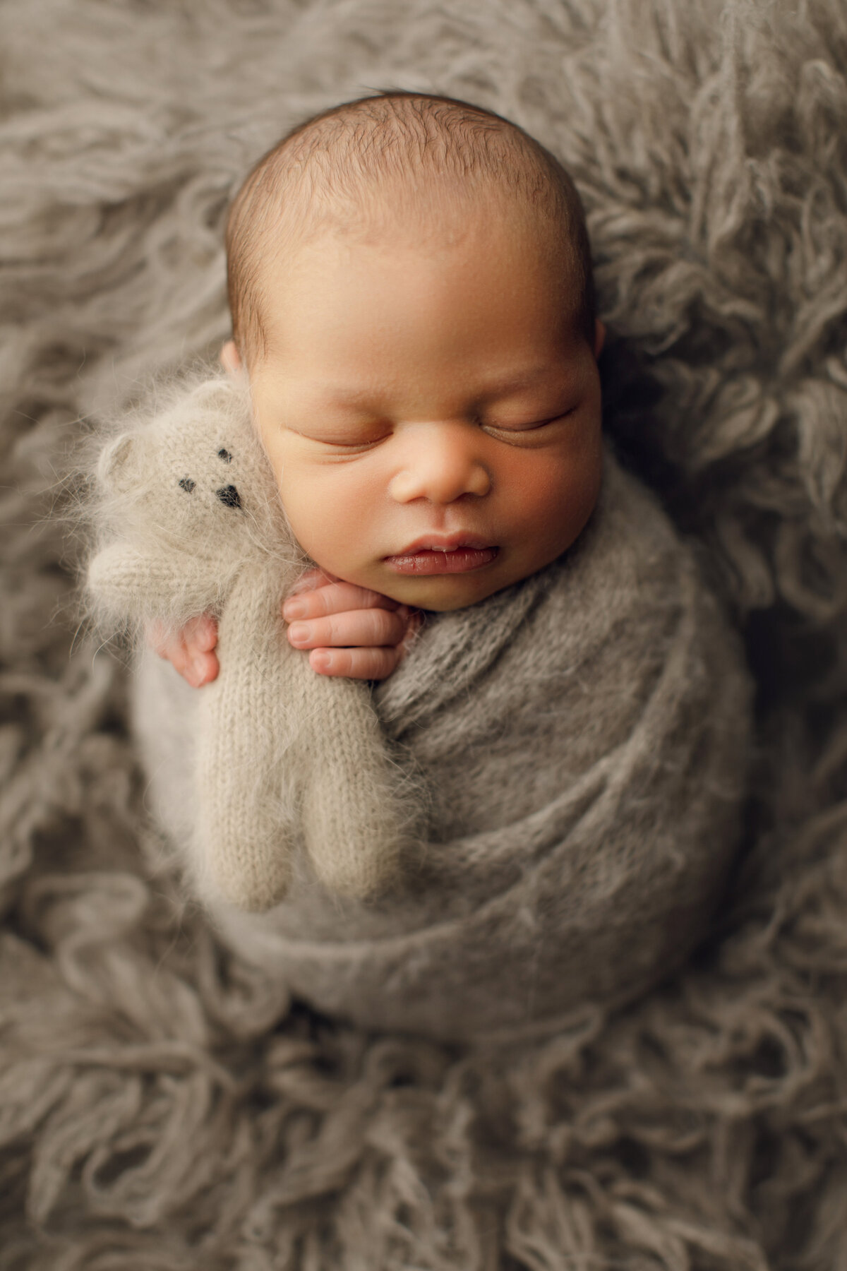african american baby boy in gray snuggling teddy bear