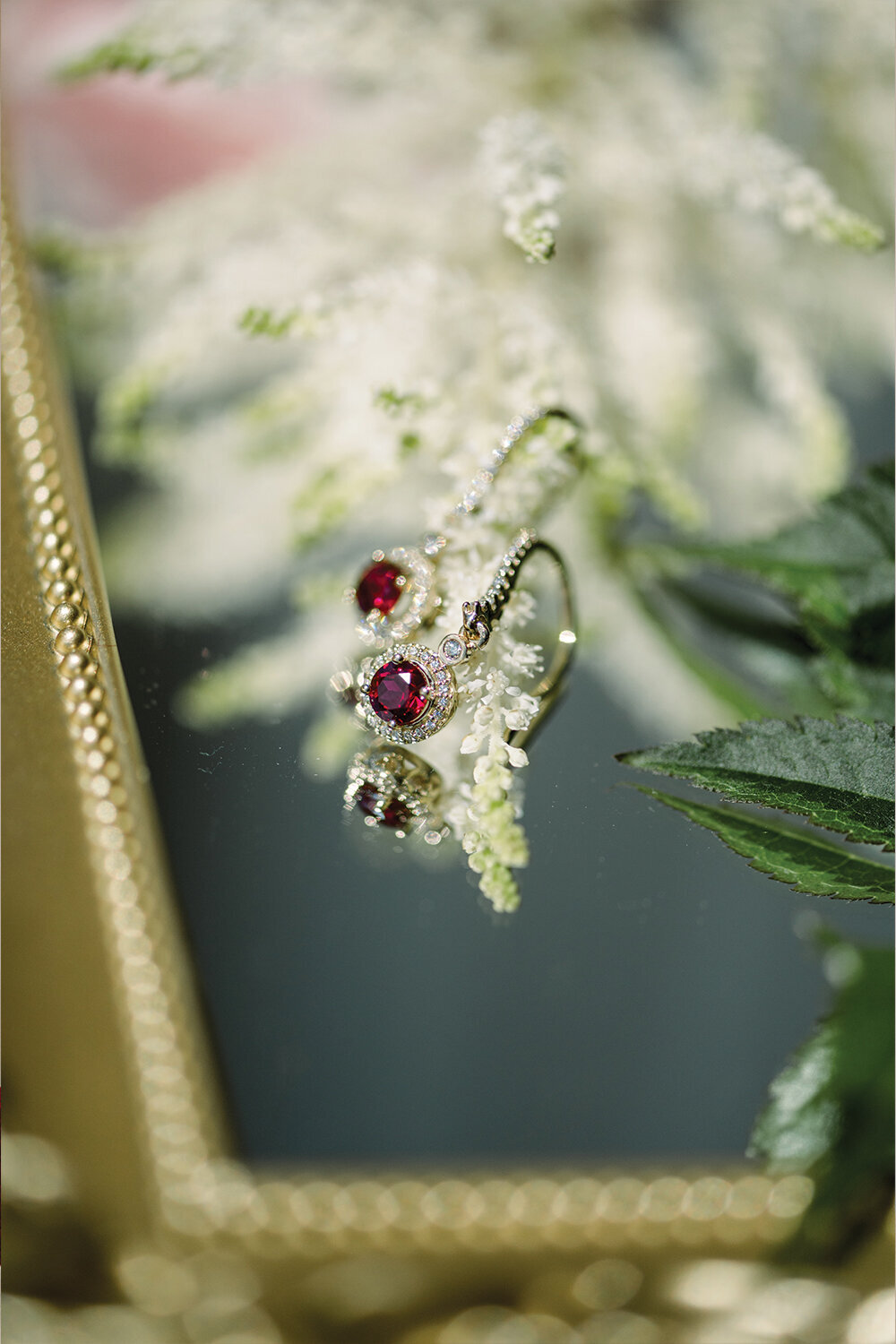 Ruby and diamond earrings displayed on a gold-framed mirror, capturing the timeless beauty and luxurious details of a 50th wedding anniversary celebration at The Northern Hotel in Billings, MT.