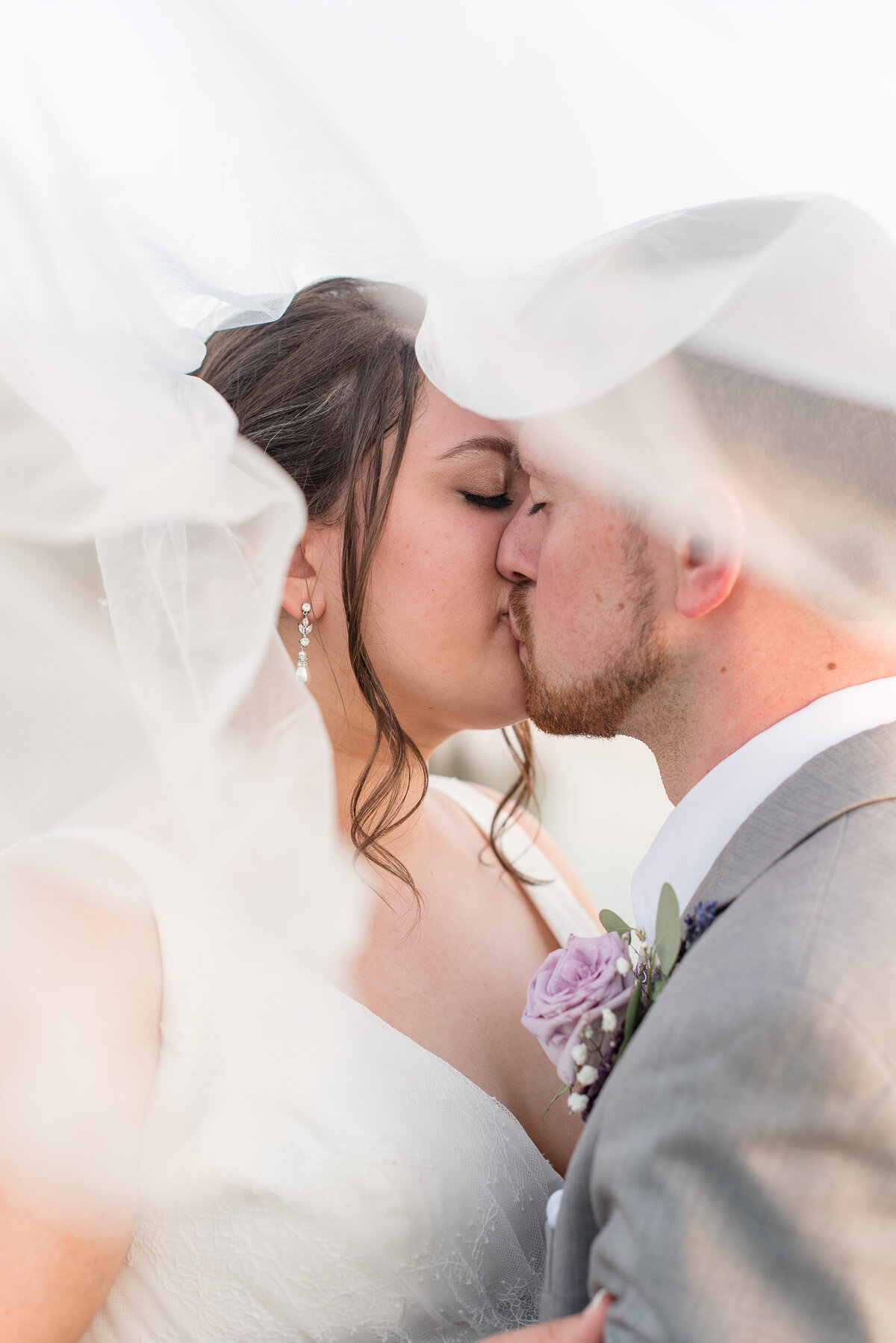 Bride and Groom kissing with eyes closed and long white bridal veil swirling around them in Lancaster, Pennsylvania.