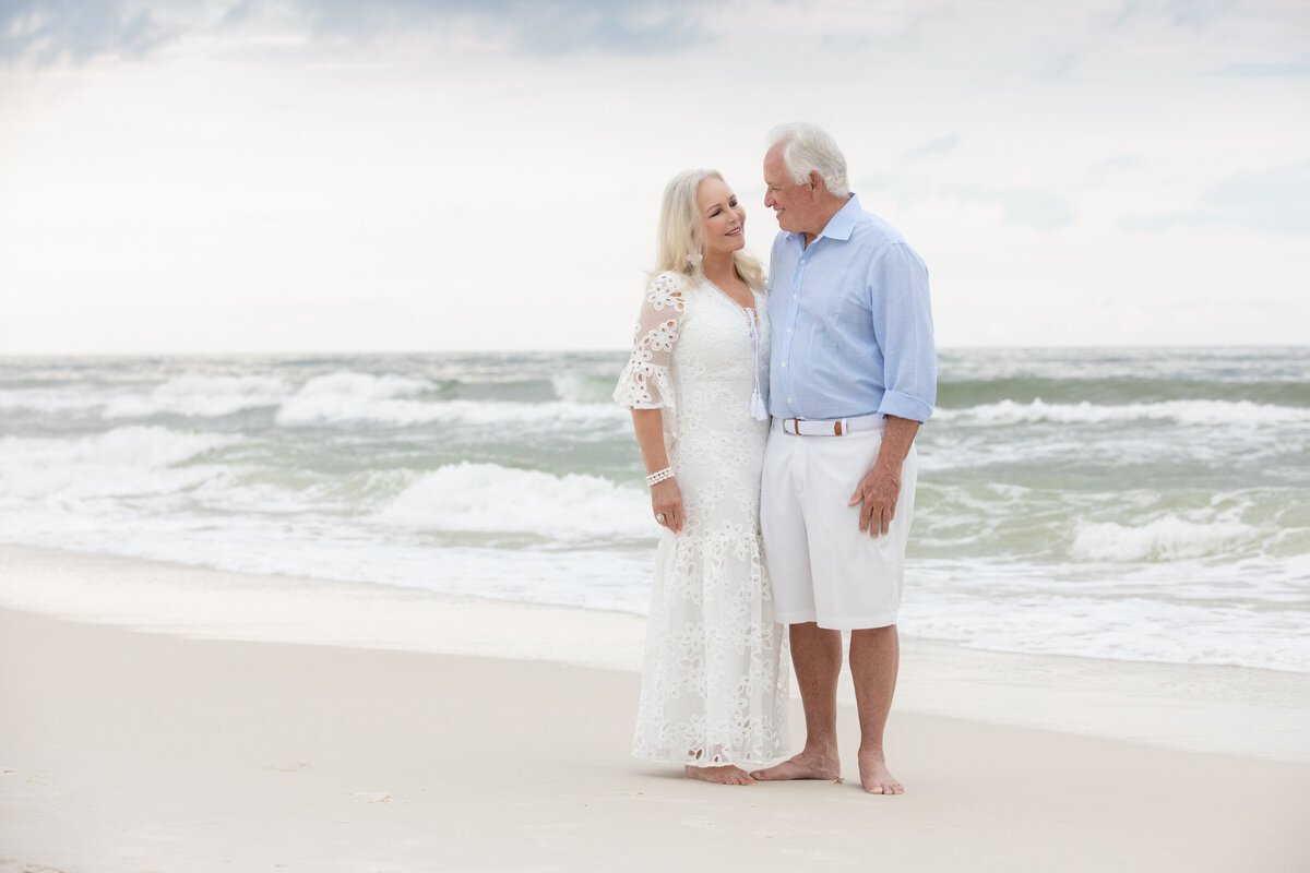 An older couple smiling and looking at each other at the beach