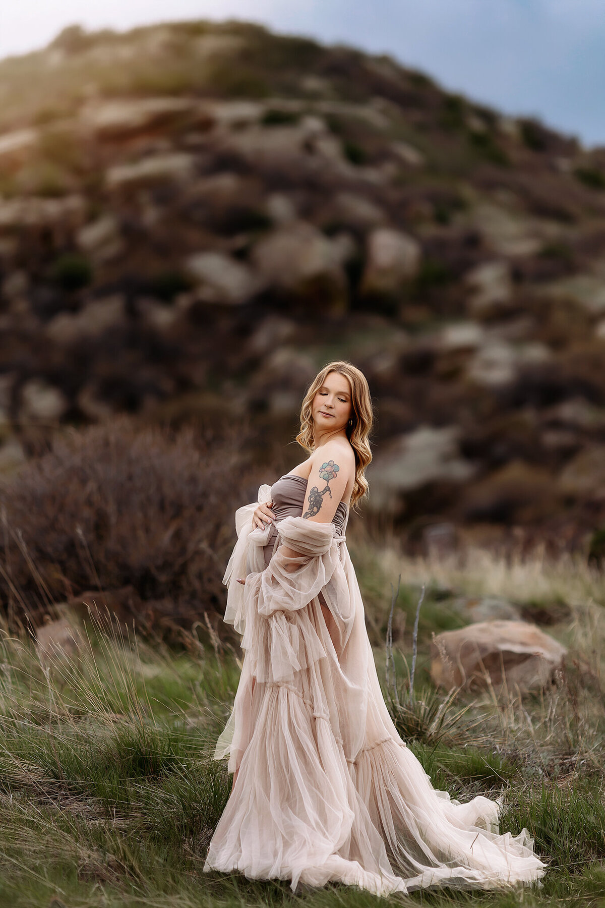 pregnant mom standing against the front range in denver colorado for her maternity photos