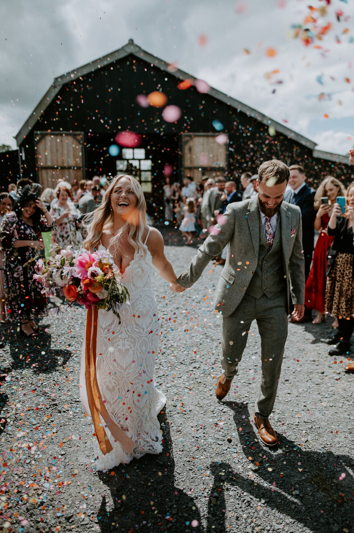 A couple exit their ceremony at The Giraffe Shed to a shower of confetti from their guests. The entire wedding was very colourful.