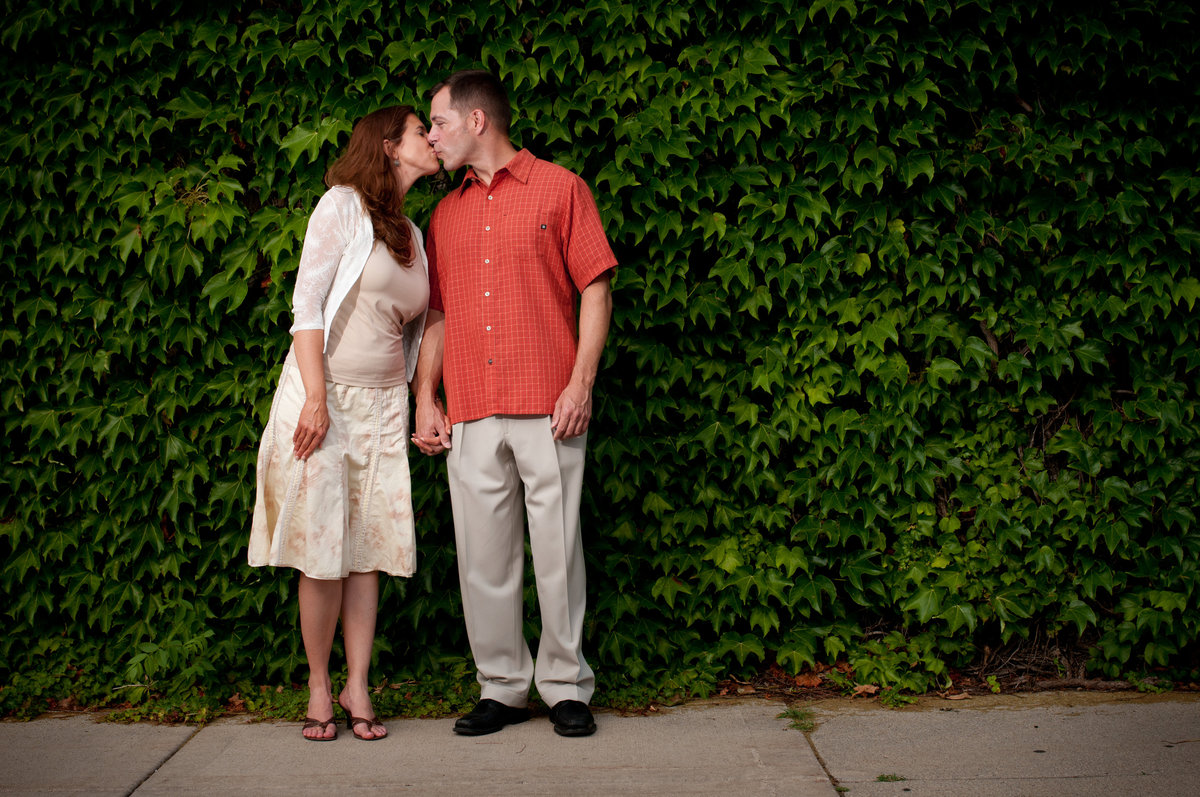 Kissing couple against an ivy covered brick wall