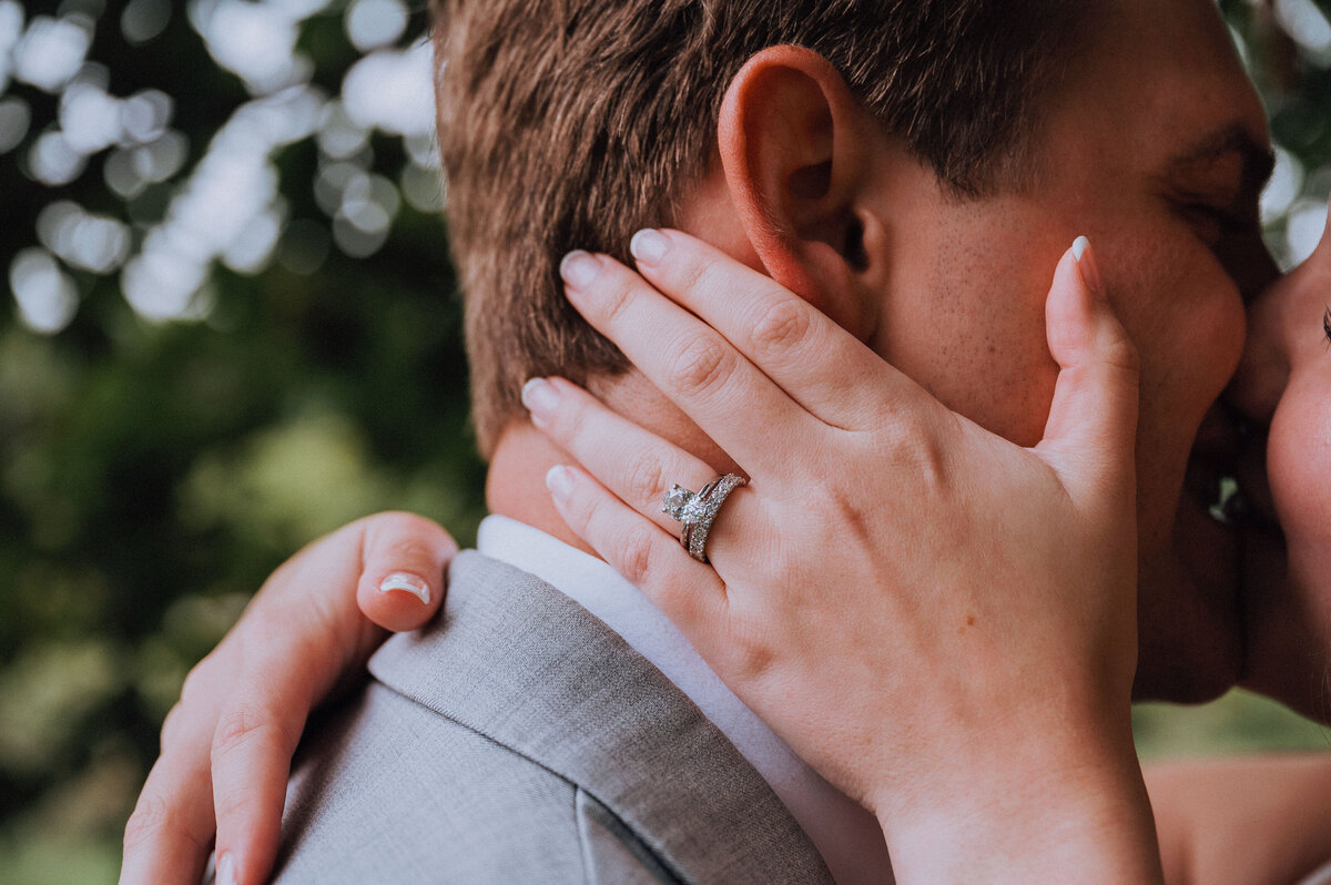 Close up photo of bride and groom kissing with focus on brides ring