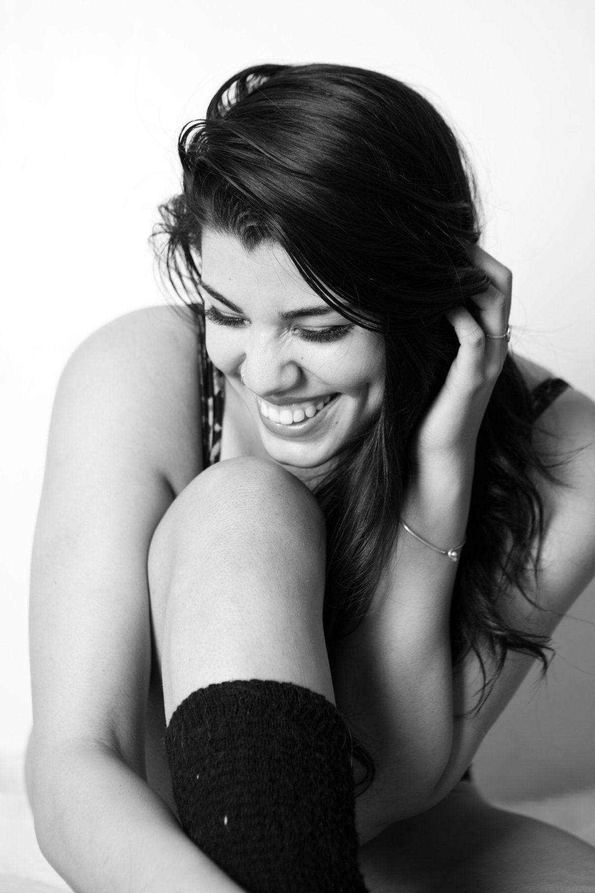 Black and white photo taken in a New York photography studio by a boudoir photographer. Woman laughing portrait.